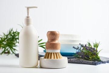 dishwashing brushes, towel and detergent on table with white walls. Home comfort. Household...