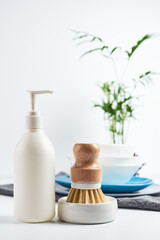 dishwashing brushes, towel and detergent on table with white walls. Home comfort. Household equipment.