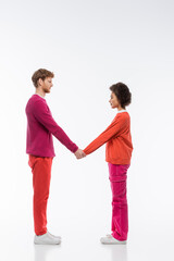 side view of interracial couple in magenta color clothes showing m letter on white background.
