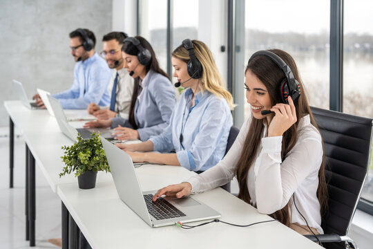 Group of friendly professional customer support operators interacting with clients while having online chats at call center office.