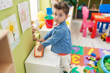 Adorable hispanic toddler playing with truck at kindergarten