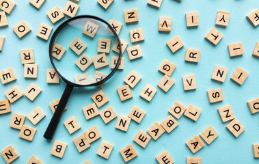 Square letter tiles with magnifying glass against blue background. Search for words and information...