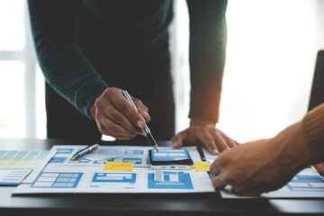 ux developers and ui designers, data researchers brainstorm on  tabletop mobile app interface wireframe design with client summary color codes the modern office Creative Digital Development Agency.