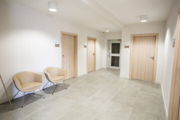 An elegant waiting room in a modern medical facility. Clinic with white walls and comfortable armchairs. Prestigious waiting room. Aesthetic medicine. Private offices.