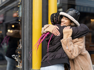 Two young women hugging in street