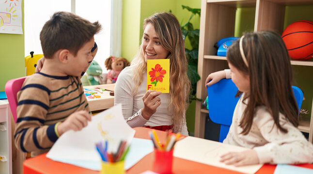 Teacher with boy and girl sitting on table having language lesson at kindergarten
