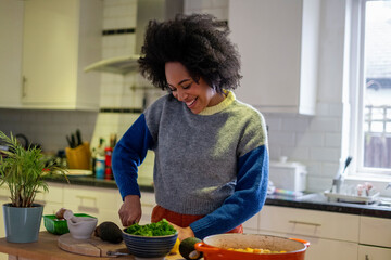 Smiling young woman cooking at home