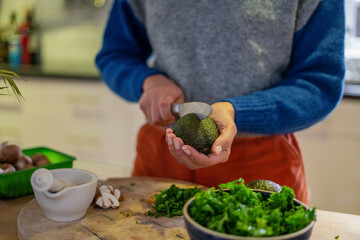 Woman cutting avocado in half at home