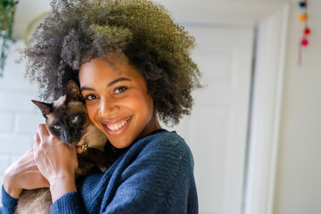 Portrait of smiling woman holding cat at home