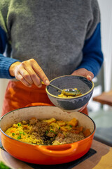 Woman putting food in bowl at home