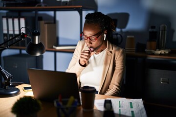 Beautiful black woman working at the office at night feeling unwell and coughing as symptom for cold or bronchitis. health care concept.