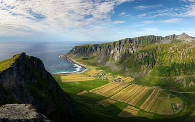 Hiker on the top of a cliff in Lofoten. Overlooking the Unstad village and beach.