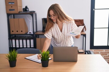 Young blonde woman business worker reading document at office