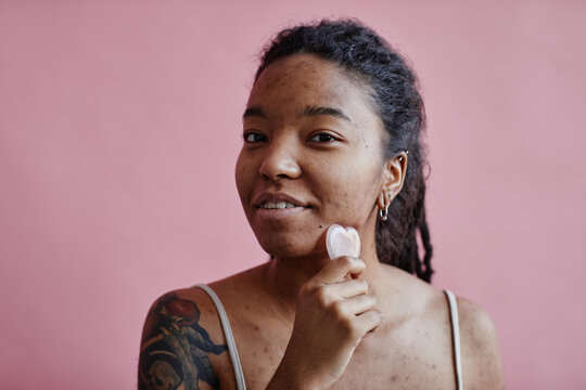 Candid Young Black Woman With Acne Scars Using Face Massager