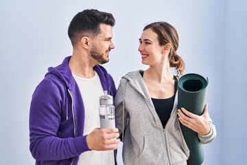 Man and woman hoilding yoga mat and bottle of water standing at sport center