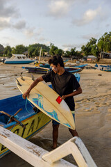 Fototapeta Indonesia, Lombok,�Male surfer packing surfboard on boat at beach obraz