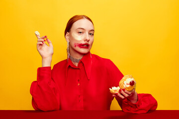 Whipped cream. Beautiful young girl in red shirt with smudged red lipstick after eating cake over yellow studio background. Food pop art photography. Complementary colors. Concept of art, beauty, food