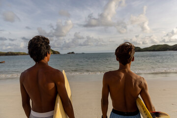 Fototapeta Indonesia, Lombok, Rear view of surfers looking at sea from beach obraz