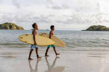 Fototapeta Indonesia, Lombok, Side view of two surfers walking with surfboards on beach obraz