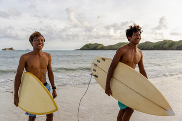 Indonesia, Lombok, Two surfers walking out of sea