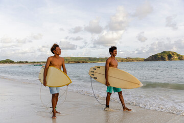 Fototapeta Indonesia, Lombok, Two surfers walking with surfboards on beach obraz