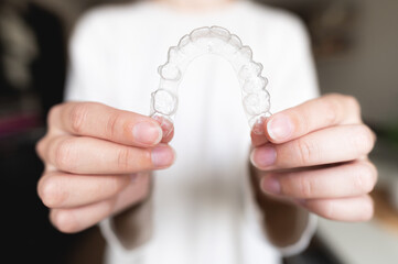 Close-up of a woman's hand holding invisible aligners for whitening and straightening teeth on a...