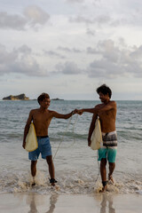 Fototapeta Indonesia, Lombok, Two surfers bumping fists while walking out of sea obraz