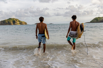 Fototapeta Indonesia, Lombok, Rear view of two surfers walking into sea obraz