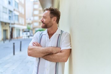 Middle age man standing with arms crossed gesture at street