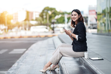 Young Asian businesswoman using mobile phone and walking in airport before business trip. Beautiful woman passenger has mobile call and discusses something with smile, holds coffee in hand