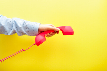 Woman hand hanging up pink phone on yellow background, communication and connection concept - obrazy, fototapety, plakaty