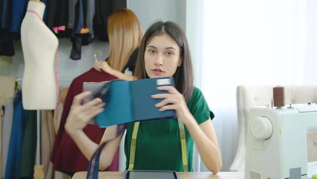 Portrait of freelance designer, tailor, stylist artist,professional caucasian women designer looking at the camera. Talking with customer show color fabric sample for customers to choose for tailoring