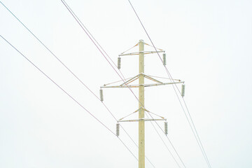 High voltage power line pole in winter. Background on the theme of energy and transmission of electricity over long distances in difficult conditions, in a cold, snowy climate.