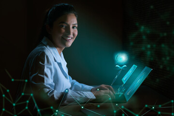 Businesswoman working on laptop computer with icons on virtual screen