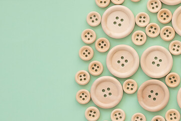 Wooden buttons on a green background. layout for creativity and hobbies. Wooden button - obrazy, fototapety, plakaty