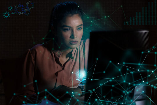 Businesswoman working on laptop computer with icons on virtual screen