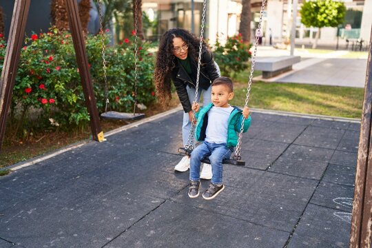Mother and son playing on swing at park