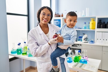 Obraz premium Mother and son wearing scientist uniform hugging each other at laboratory