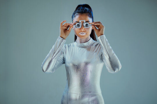 Model dressed as a silver robot Holding prosthesis looking at camera on grey background