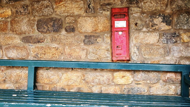 Red post-box in stone wall with bench