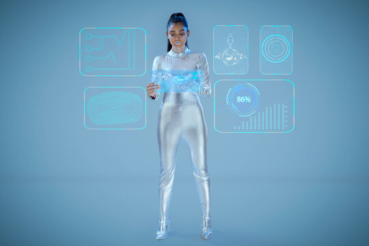 A model dressed as a robot wearing silver, futuristic  clothes holding a virtual  tablet, with virtual icons . A future technology concept