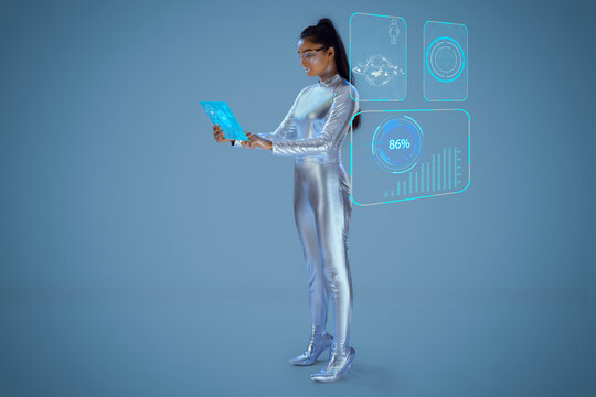 A model dressed as a robot wearing silver, futuristic clothes holding a virtual tablet, with virtual icons . A future technology concept