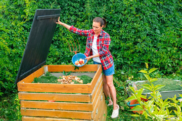 Food waste in a compost bin. A woman in a plaid shirt throws kitchen waste into a DIY compost bin....