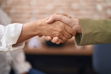Two women business workers shake hands for agreement at office
