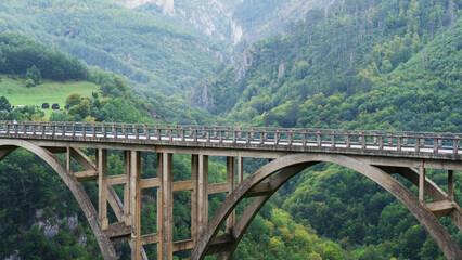 Obraz premium An old concrete suspension bridge over the river on the background of mountains. Panoramic photography, beautiful nature.