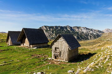 Three houses in the sunlight on the background of mountain peaks