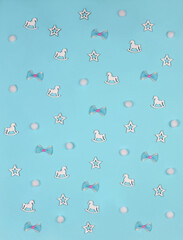 Light blue kids background with rocking horses, bows, white  stars and snow balls. top view, flat lay.