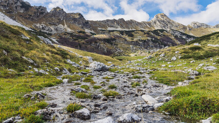 Mountain stream in good weather. Mountain landscape and sky with clouds