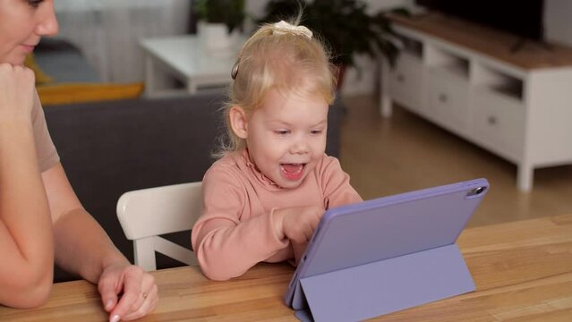 A child with cochlear implants plays with a tablet computer with his mother. Deafness and medical technology concept