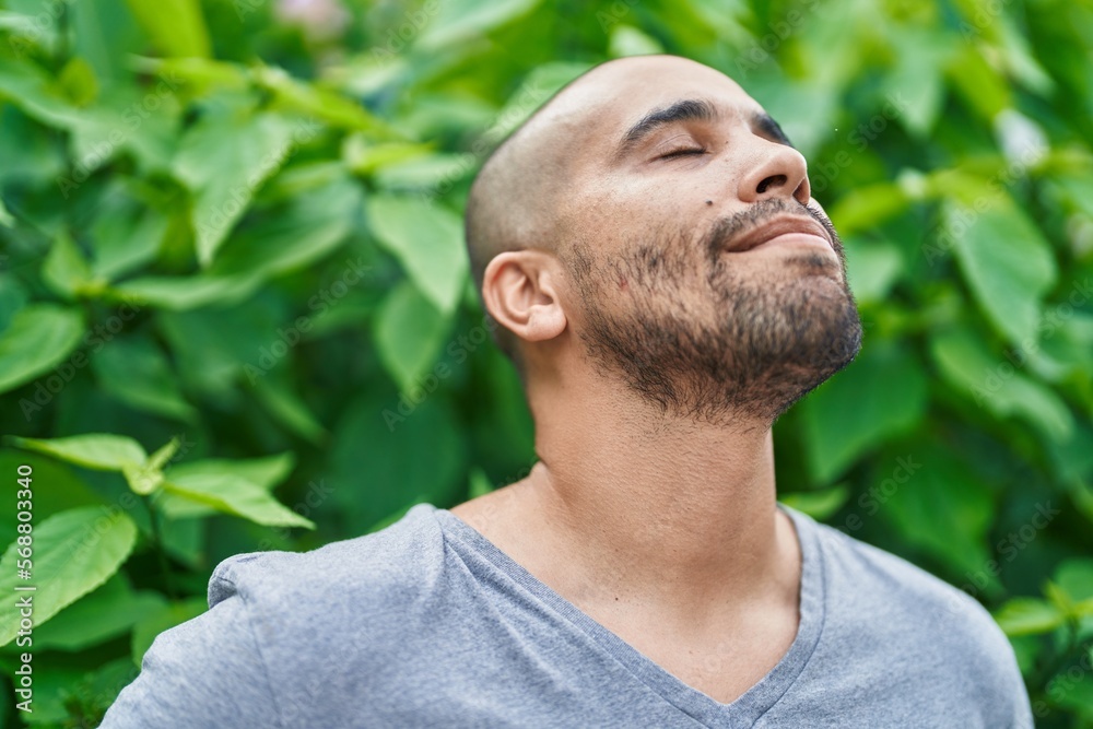 Poster Young latin man breathing with closed eyes at park